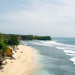 An image of Balangan Beach with pristine golden sands and waves crashing along the shore.