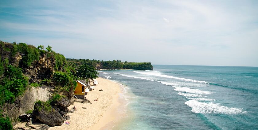 An image of Balangan Beach with pristine golden sands and waves crashing along the shore.