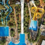 A bird’s eye view of a leisure hub featuring lush green vegetation and colourful rides.