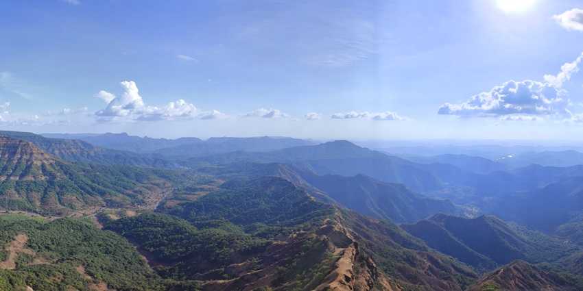 A mesmerising view of a lush green hill station with scenic trails on a clear day