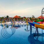 Children squealing with delight while sliding down colourful water slides at the water park in Pune