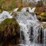 The Khandi Waterfalls is a natural marvel surrounded by greenery and rocky terrain.