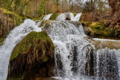 The Khandi Waterfalls is a natural marvel surrounded by greenery and rocky terrain.