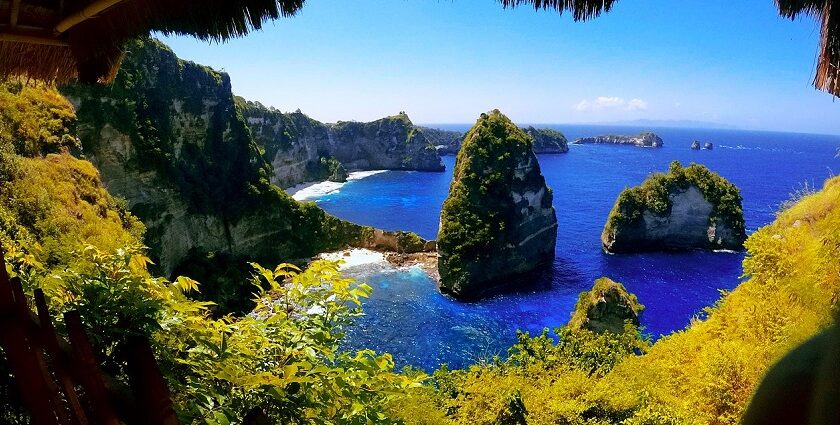 The view of this sland from inside a cave with rugged cliffs, one of the best places to visit in Nusa Penida.