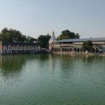 A picture of a temple in Solapur with a lake surrounding it