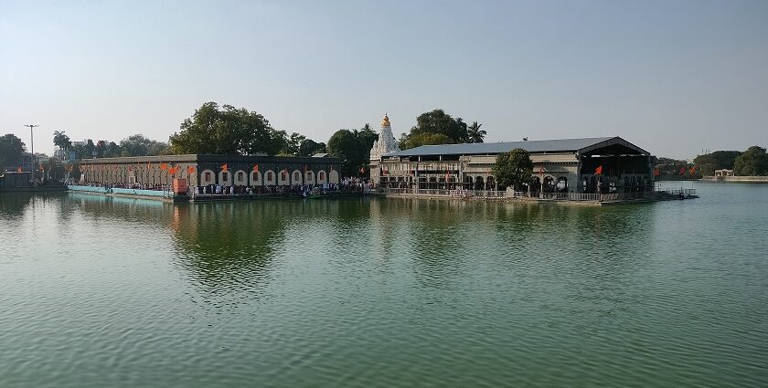 A picture of a temple in Solapur with a lake surrounding it