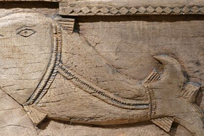 Shape of a fish carved on wood with border designs displayed in Sudarshan Crafts Museum.