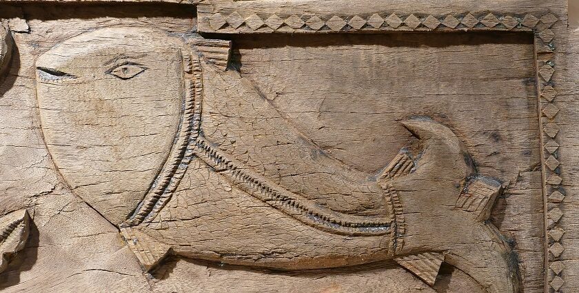 Shape of a fish carved on wood with border designs displayed in Sudarshan Crafts Museum.