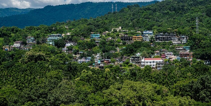 A picture of a house situated in a green hilly area right under the cloudy skies.