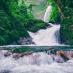 The breathtaking Vajrai Waterfalls flowing down a mountain, framed by greenery and rocky terrain.