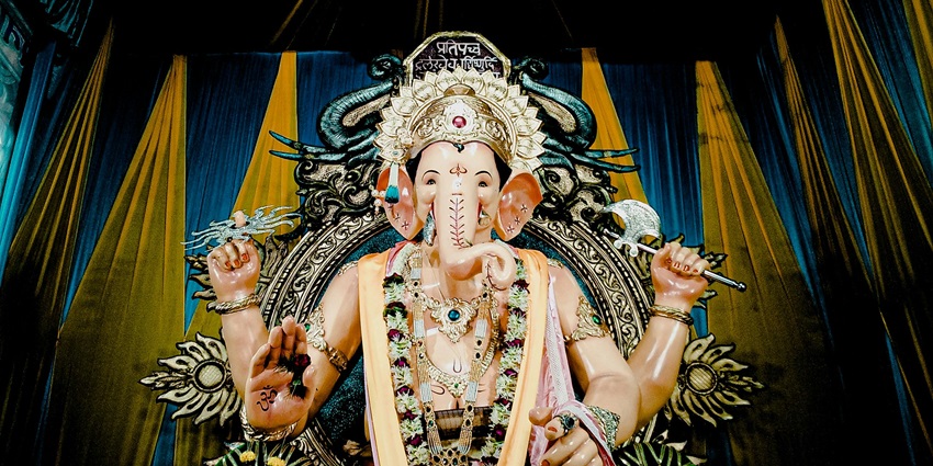 A picture of a tall idol of Lord Ganesha decorated with garlands and flowers in a temple