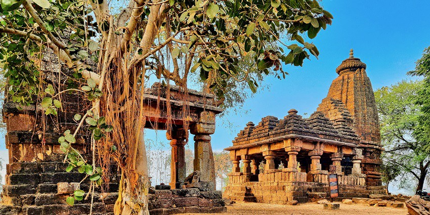 View of the Adasa temple with a big tree in the front and blue sky in the background