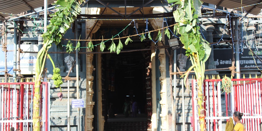 Sowmya Narayana Perumal Temple entrance gate decorated with leaves and a woman praying outside