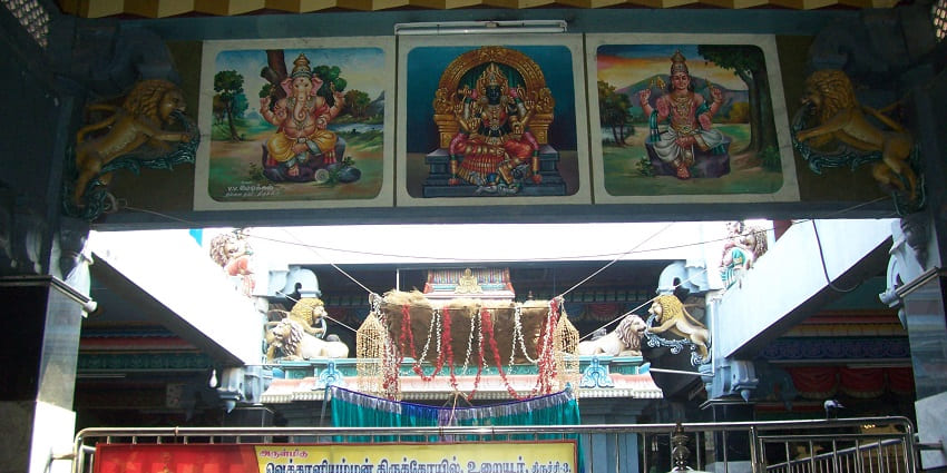Inside view of Vekkaliyamman Temple, featuring photos of deities and an information banner.