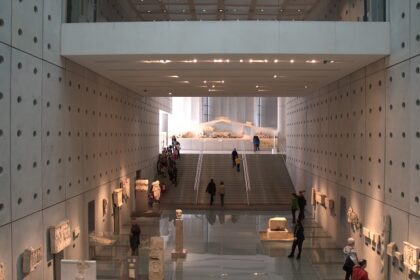 Interior of Acropolis Museum with stairs, first floor and people exploring the antiques.