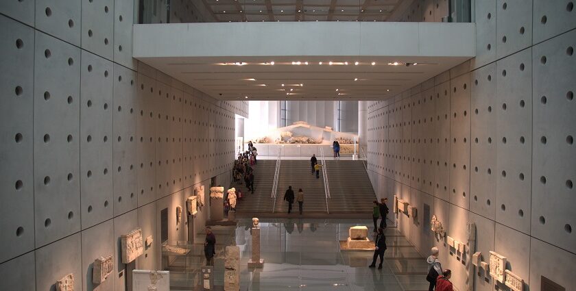 Interior of Acropolis Museum with stairs, first floor and people exploring the antiques.