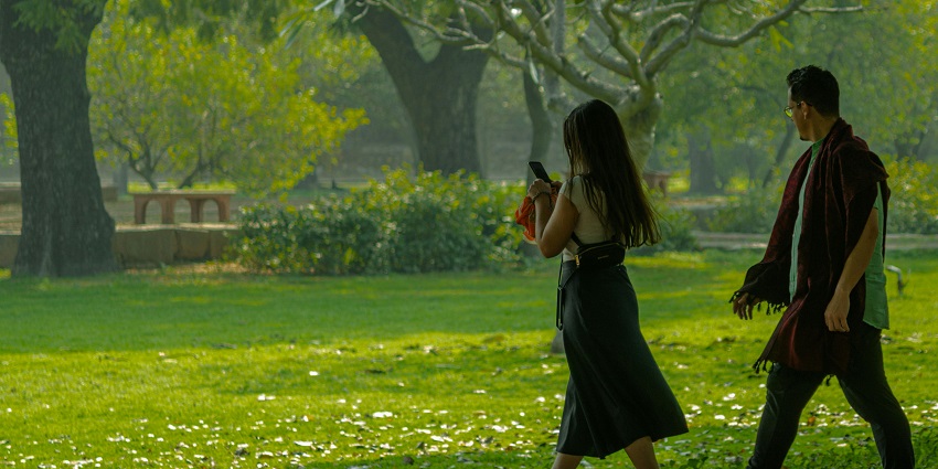 A couple walking hand in hand, the best thing to do in Madurai, through a lush green park.