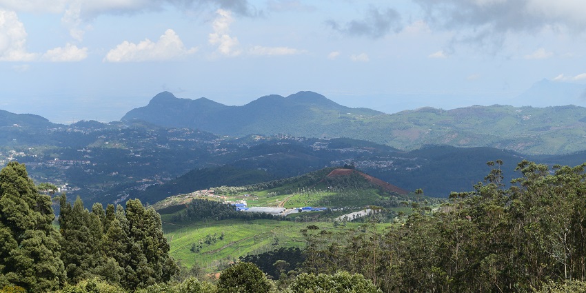 A panoramic view of the Nilgiri Hills from Doddabetta Peak, featuring rolling green hills.