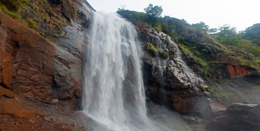 View of Aagai Gangai Falls flowing down a rocky hillside, surrounded by dense green forest