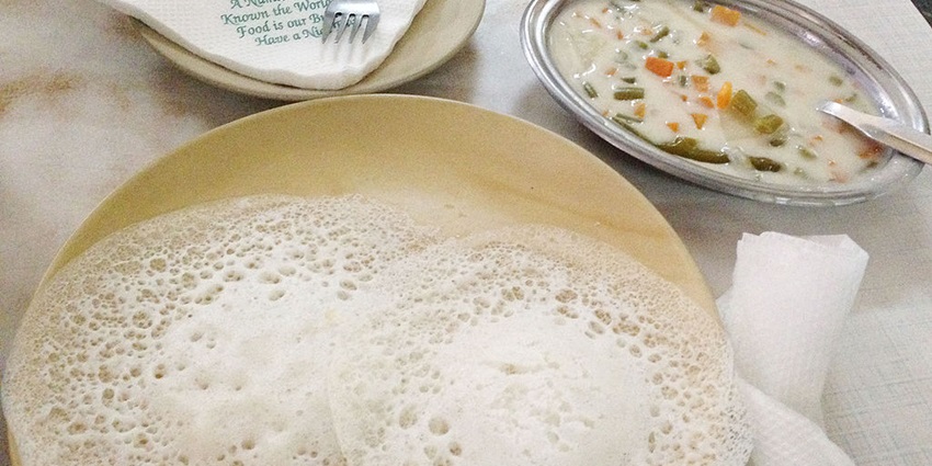 Soft, fluffy rice pancakes served with flavorful vegetable stew on a white plate.