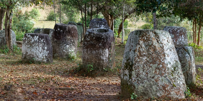 Ancient stone scattered across a forest clearing, partially covered in moss and lichen