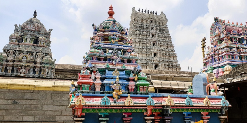 A picture of a traditional Hindu temple with colourful walls and a beautiful Gopurama
