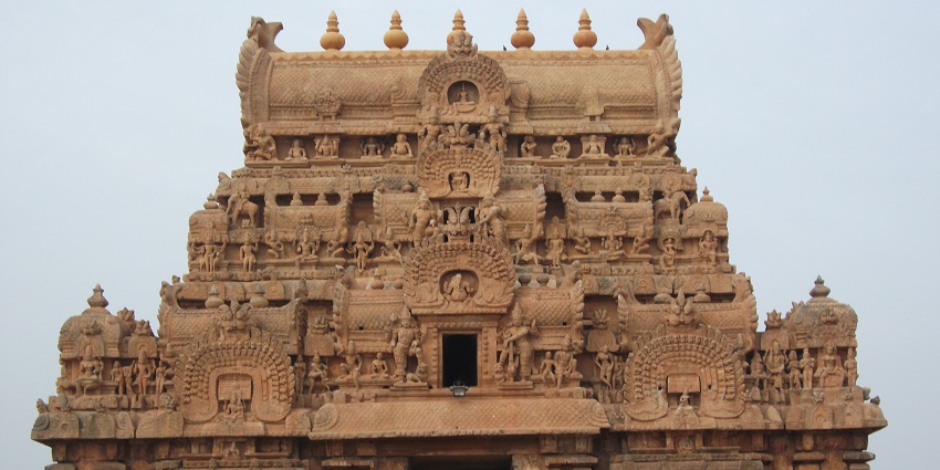 An outside view of the entrance of a temple which is beautifully carved from stones.