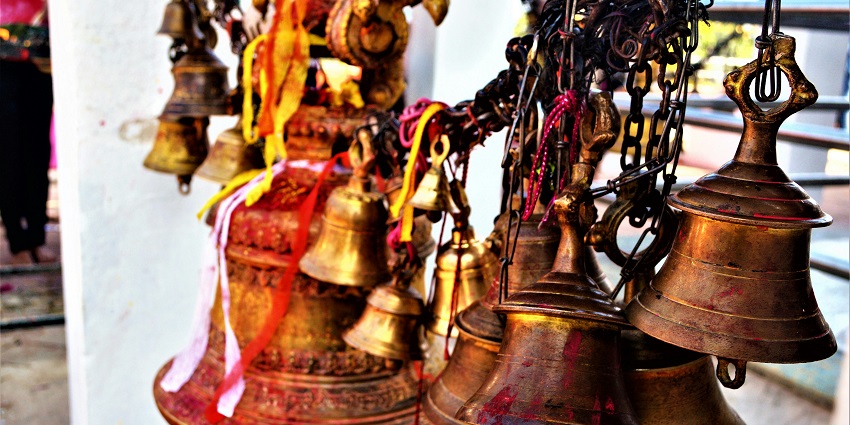 Close-up of a brown metal bell hanging in a temple in India.