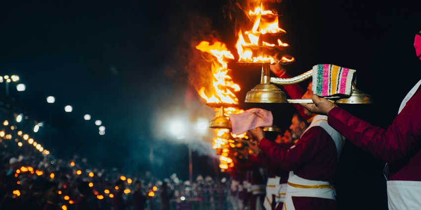 A glimpse of saints performing the iconic Ganga aarti near the shimmering river.
