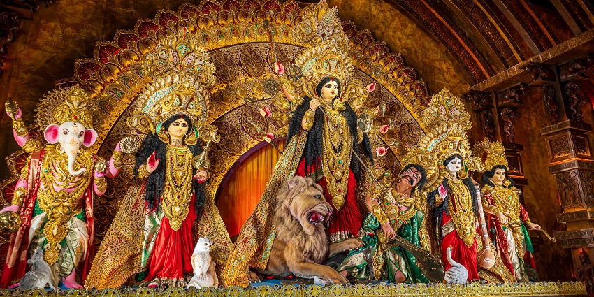 A tall pandal having idols of various Hindu deities, decorated with flowers and garlands during a festival