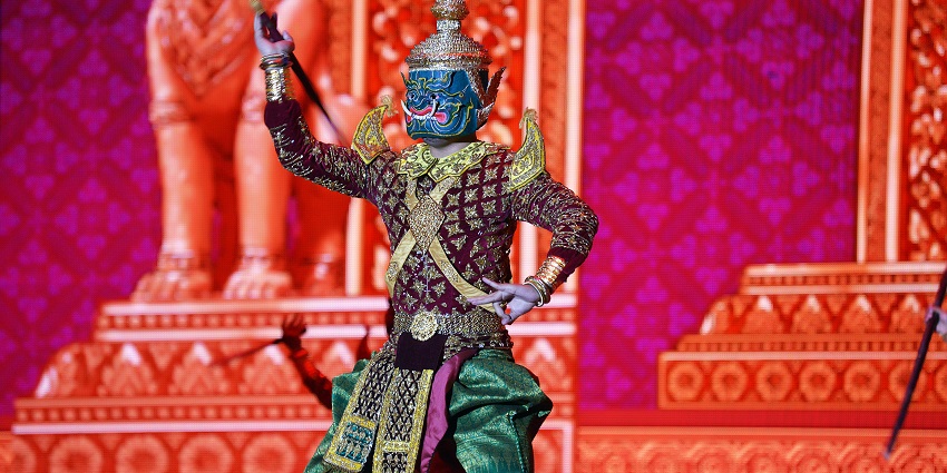 A picture of a performer in a decorated outfit and a mask performing on the stage.
