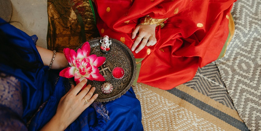 Close-up shot of a hand over a traditional worship tray containing ceremony items.