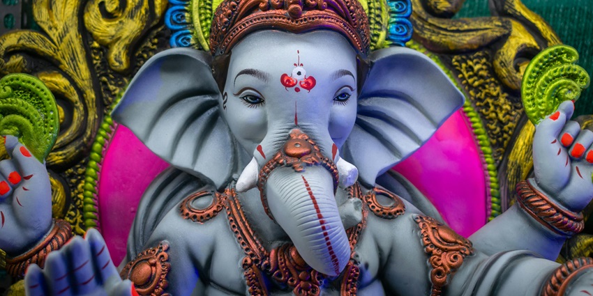 A picture of an idol of Lord Ganesha at a temple being offered Aarti from the devotees