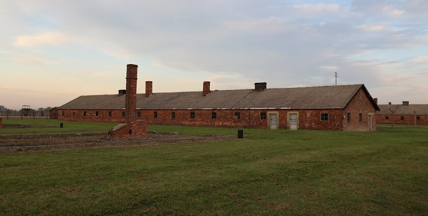 Auschwitz-Birkenau State Museum with barracks and old structure surrounded by greenery.