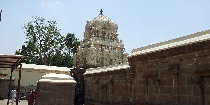 Entry to a white-coloured temple with brown brick walls, similar to Sivanmalai Temple.