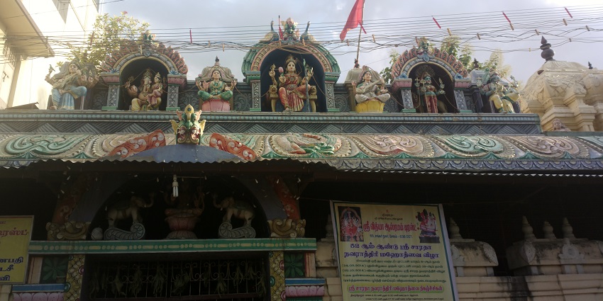 An outer view of a religious site on the top of which there are idols of various deities