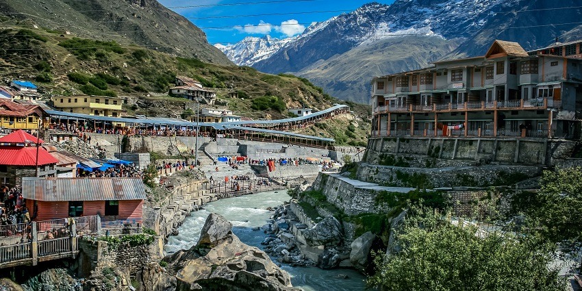 A serene view of Badrinath featuring majestic peaks, shimmering waters, and houses.
