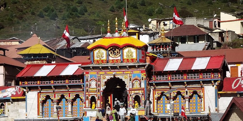 A beautiful view of Badrinath Temple in Uttarakhand, India, surrounded by green mountains and blue sky.