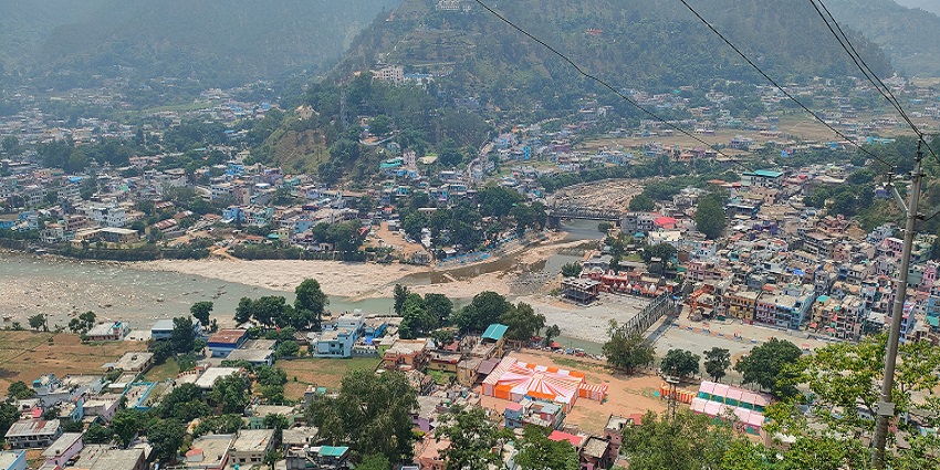 A panoramic view of Bageshwar from Chandika Temple, showcasing mountains and a clear sky.