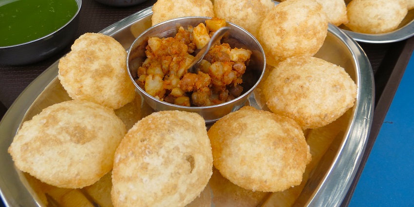 Two plates of puri are presented along with filling and two types of flavoured water