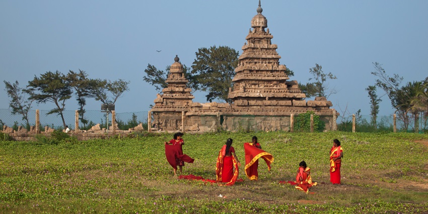 Temple framed by ocean waves and ancient stone carvings similar to Balkeshwar Temple