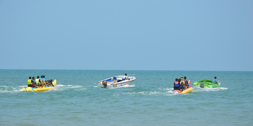 A fun image showing friends laughing together on a banana boat ride at Kihim Beach.