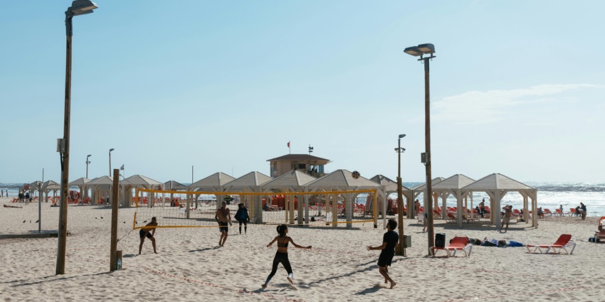A lively picture showcasing friends playing beach volleyball against a backdrop of sandy shores.