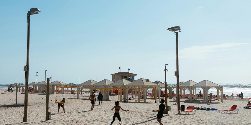 An image showing beachgoers playing volleyball on the sandy shores of Juhu Beach.