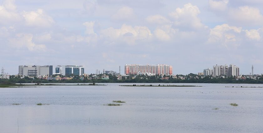 Aerial view of Chennai cityscape with tall buildings and lush greenery in the foreground.