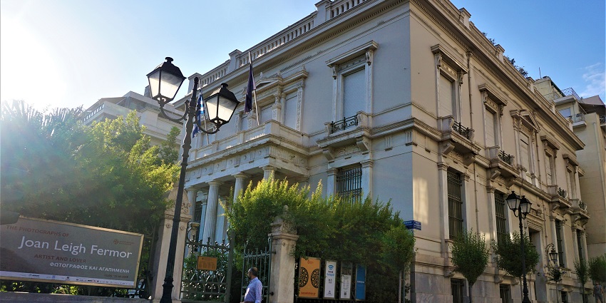 The entrance of Benaki Museum with the street lamps and a person entering the museum.