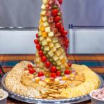 A picture of a salad dressing with numerous fruits and vegetables served in a decorative manner