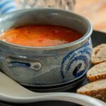 A picture of a cup of soup served alongside bread at a restaurant in Meerut