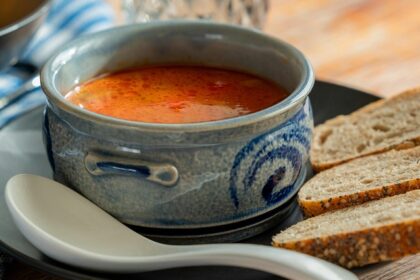 A picture of a cup of soup served alongside bread at a restaurant in Meerut