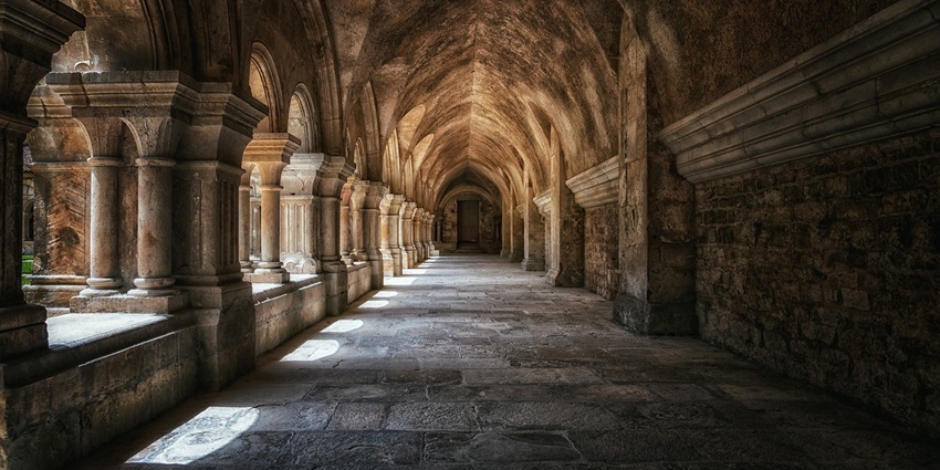 A view of a monastery featuring vaulted ceilings and a series of elegant columns